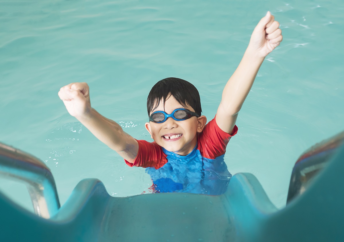 enfant-heureux-asiatique-jouant-curseur-dans-piscine